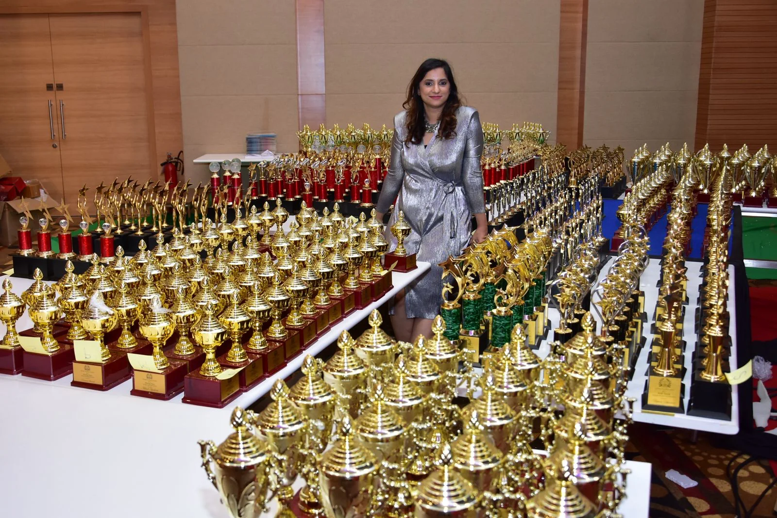 Nidhi Raina standing beside a large collection of awards and trophies