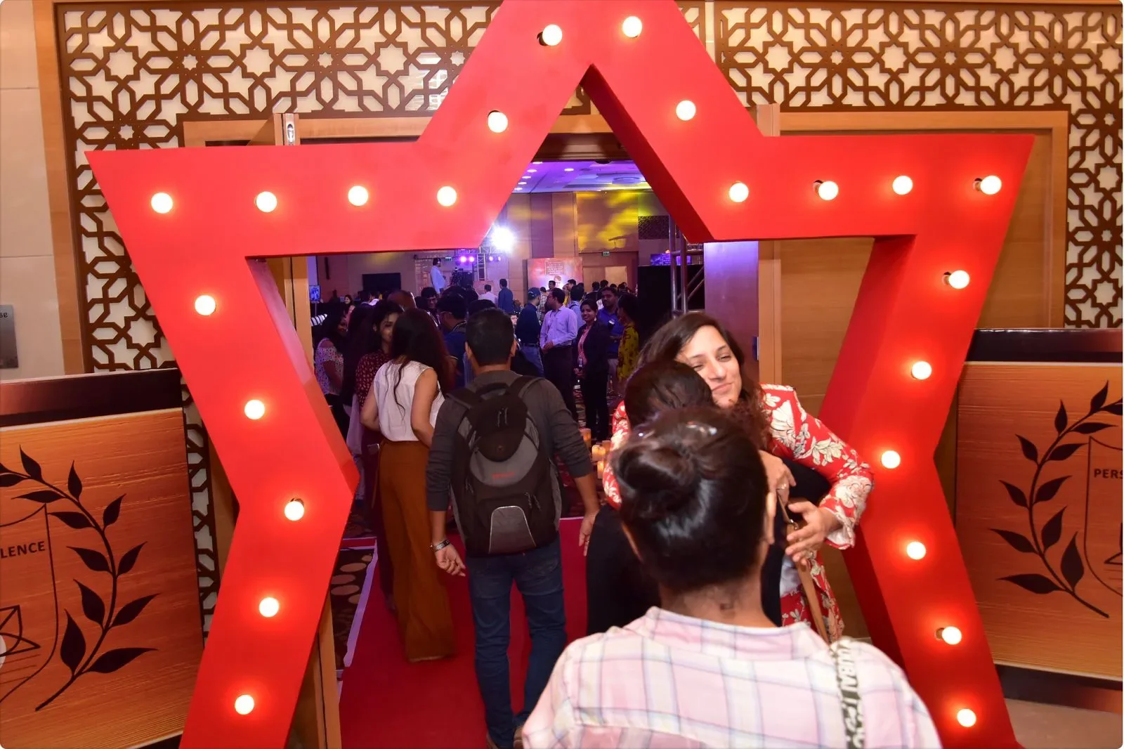 Nidhi Raina embracing an attendee beneath an illuminated star at a Personal Excellence gathering